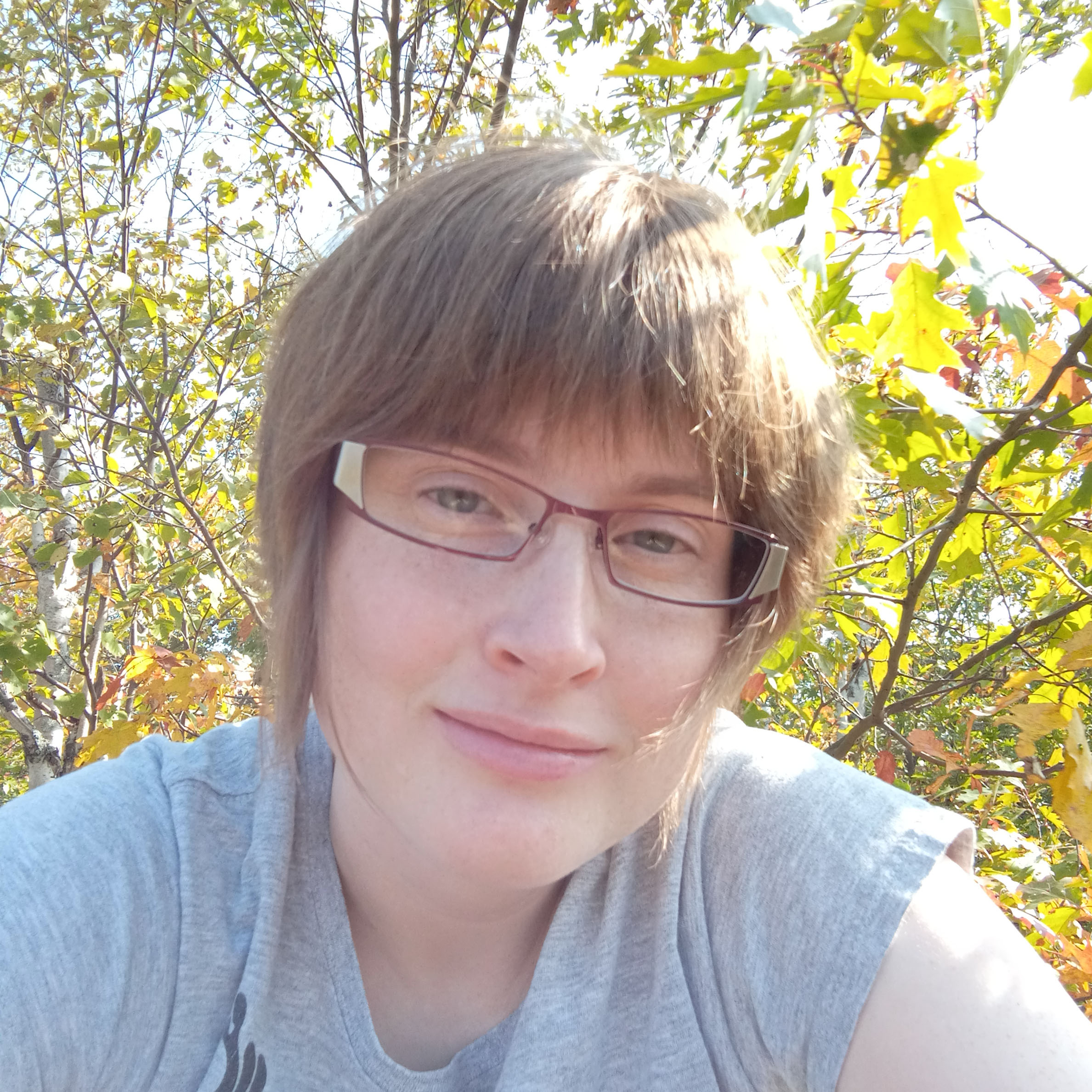 white woman with glasses, smiling.